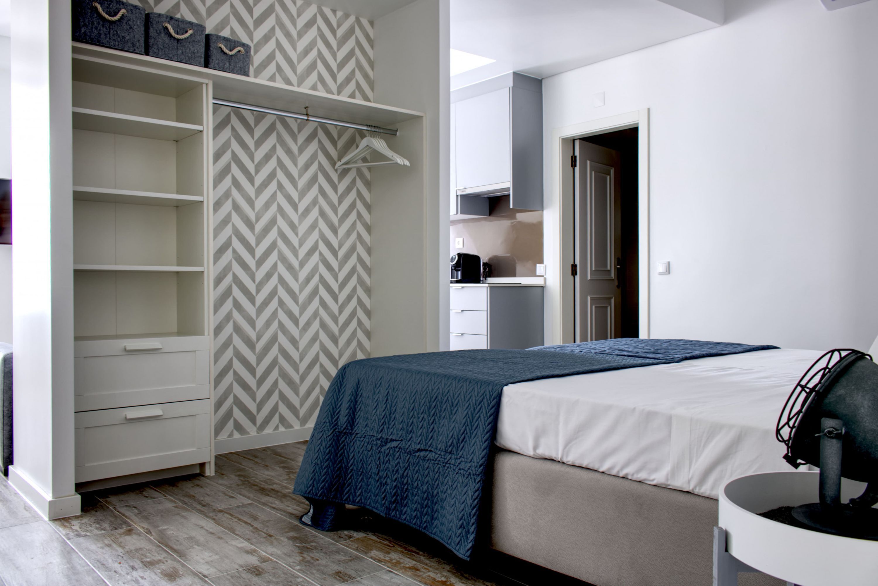 A bedroom with a bed, a wardrobe, and a kitchenette.