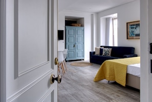 Quarto com cama, sofá azul, cadeira branca e armário azul.