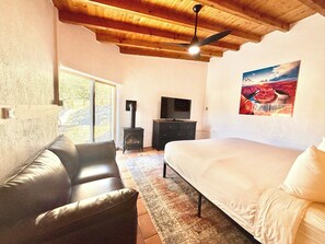 A bedroom with a bed, a sofa, a TV, and a fireplace.