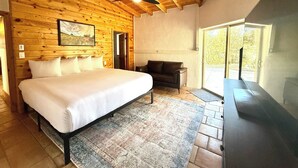Ein Zimmer mit Holzwänden, einem Bett, einer Ledersofa und einem großen Fenster.