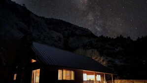 A cabin with a metal roof, wooden walls, and a porch with a bench.