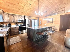 Una cucina moderna con mobili in legno, elettrodomestici in acciaio inossidabile e un'area bar con sgabelli.