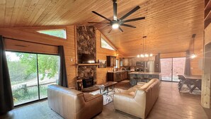 A spacious living area with a fireplace, leather sofas, and a large dining table.