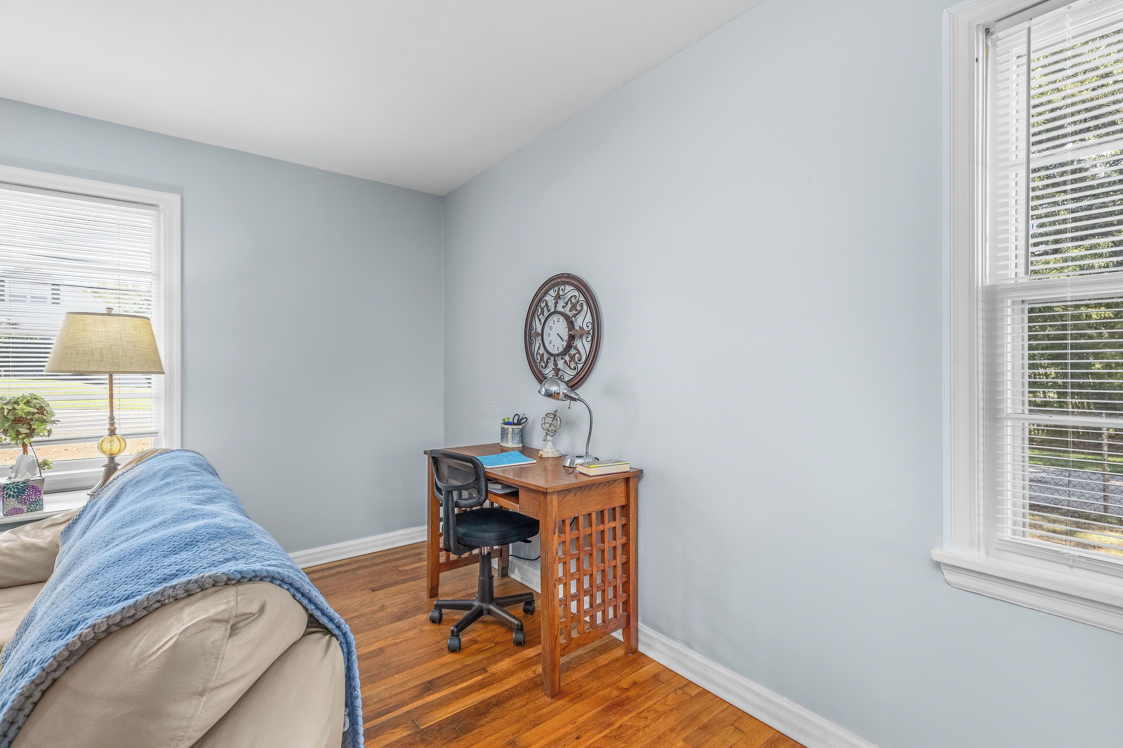 Une pièce comprenant un bureau, une chaise et une horloge au mur.