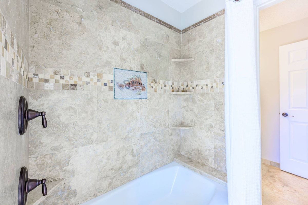Ein Badezimmer mit Badewanne, geflieste Wände und einer Duschkabine.