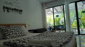 A bedroom with a bed, a headboard, a wall with a quote, and a view of greenery outside. - Oceana Inn Maldives (Kudahuvadhoo)