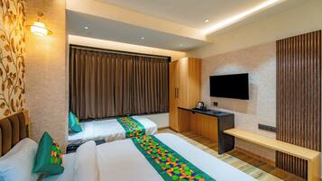 Habitación de hotel con dos camas, un escritorio, un televisor de pantalla plana y un banco de madera.