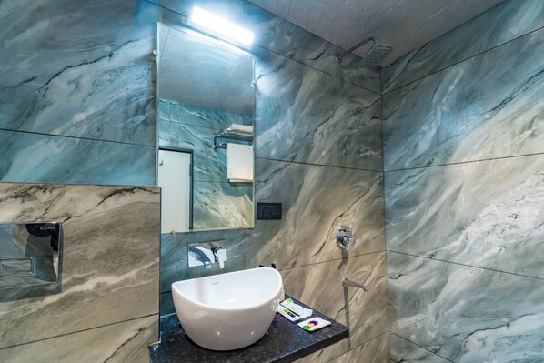 A bathroom with a white sink, marble walls, and a mirror. - Treebo Neel Orchid (Ujjain)