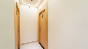 Ein schmaler Korridor mit Holztüren und Fliesenboden.