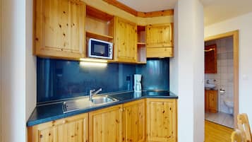 Una cocina compacta con armarios de madera, microondas, fregadero y cafetera.