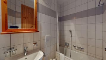 A bathroom with a sink, mirror, and bathtub.