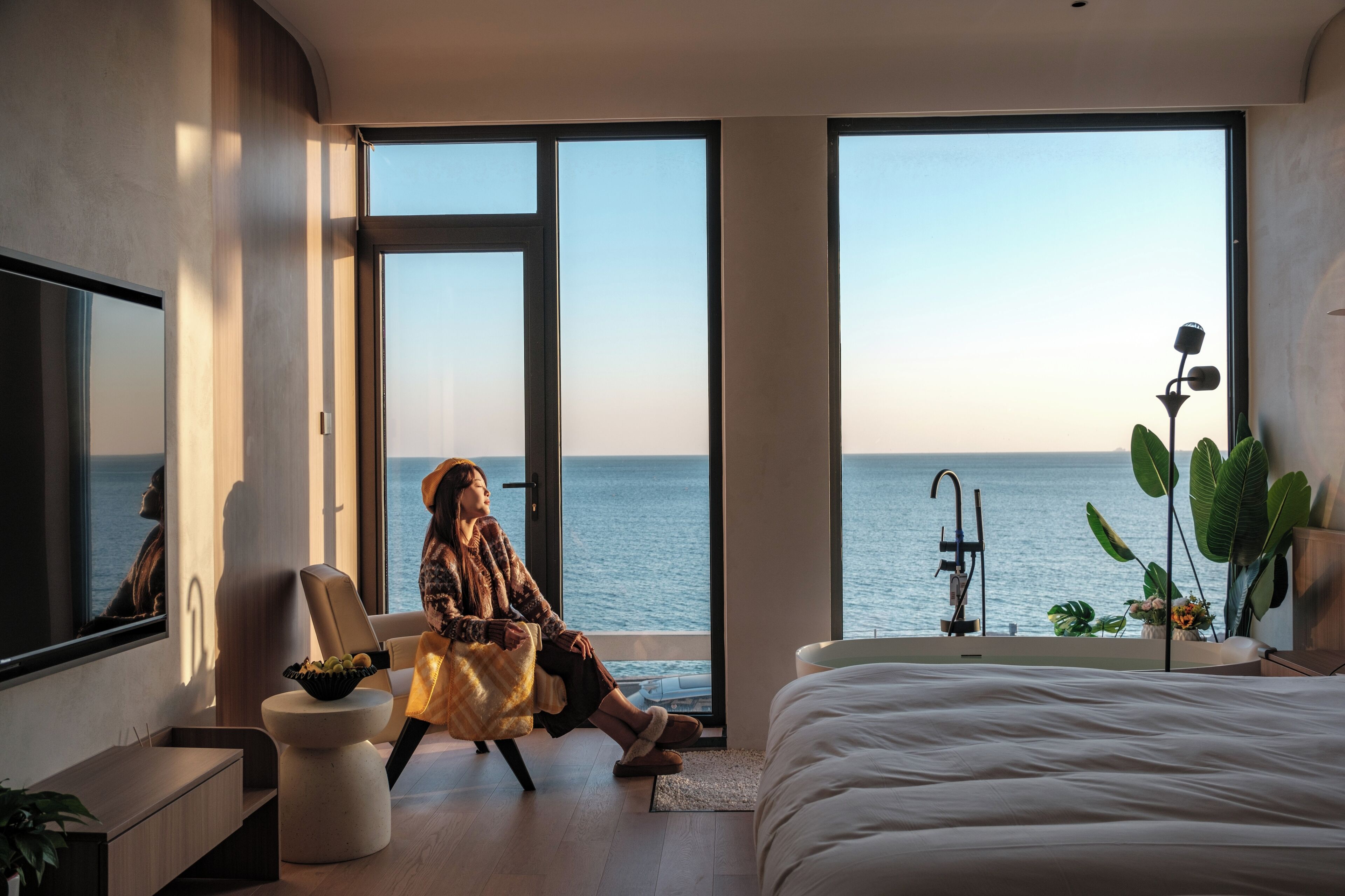 Une chambre moderne avec un grand lit, un coin salon offrant une vue sur la mer et une baignoire.