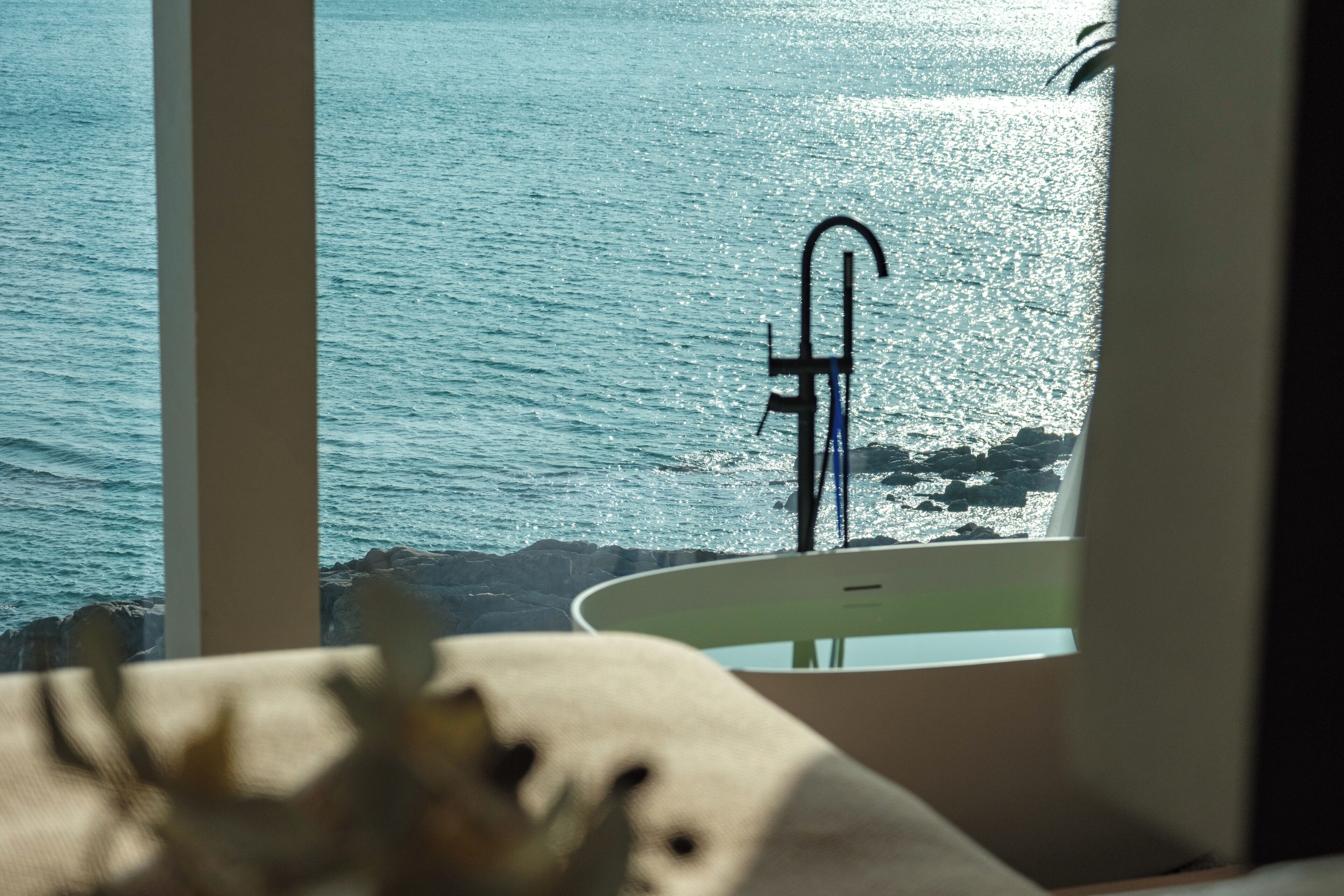 Ein Badezimmer mit einer Badewanne und Meerblick durch ein Fenster.