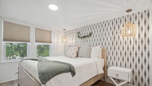 Un dormitorio con cama, mesita de noche y dos lámparas colgantes.
