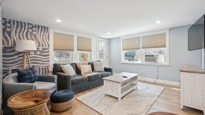Una sala de estar moderna con un sofá gris, una mesa de centro de madera y una alfombra estampada.