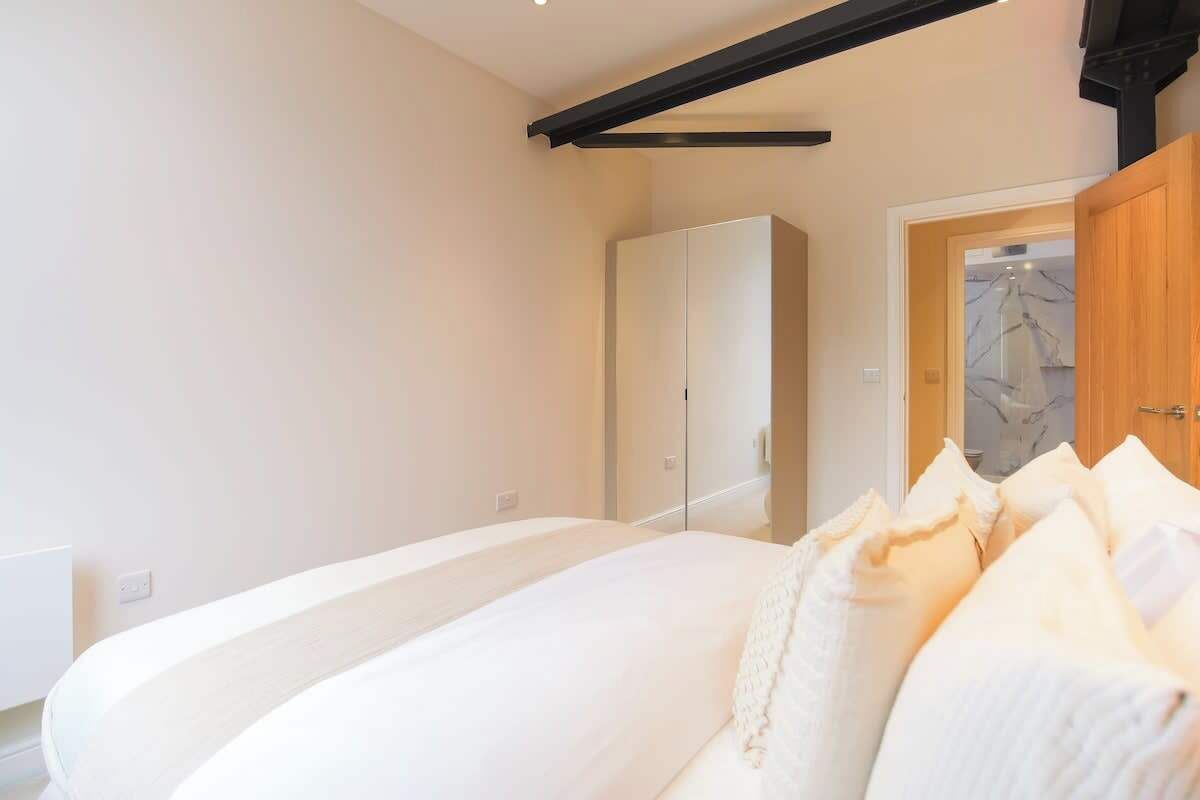 Un dormitorio con una cama grande, un armario y una puerta que da a un baño.