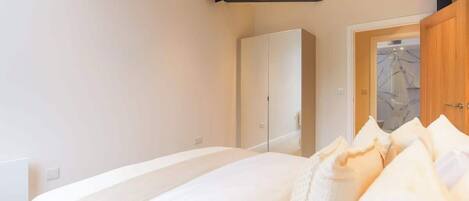 Un dormitorio con una cama grande, un armario y una puerta que da a un baño.