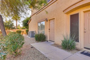 A building with two doors, a small garden with gravel and plants, and a concrete pathway leading to the entrance.