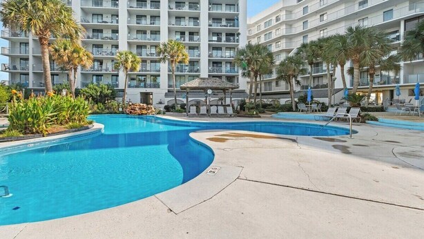 A modern hotel with a large pool area, palm trees, and lounge chairs. - 2BR Boat Friendly Condo Updated Pool Beach Access (Gulf Shores)