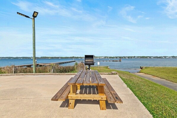 Een houten picknicktafel met een barbecue voor een waterpartij.
