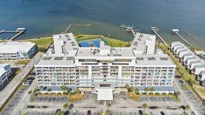A multi-story hotel with a central courtyard, parking area, and waterfront view. - 2BR Boat Friendly Condo Updated Pool Beach Access (Gulf Shores)
