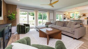 A modern living room with a sofa, a coffee table, and a TV. - Chic Creekside Bungalow at The Dogwood (Maggie Valley)