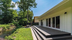 A modern house with a deck, a small garden, and a stream. - Chic Creekside Bungalow at The Dogwood (Maggie Valley)