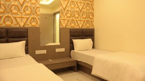 A hotel room with two beds, a built-in headboard, a mirror, and a geometric patterned wall. - Hotel NS Residency (Ahmedabad)