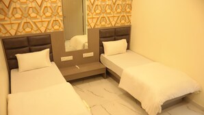 A hotel room with two single beds, a mirror, and a patterned wall. - Hotel NS Residency (Ahmedabad)