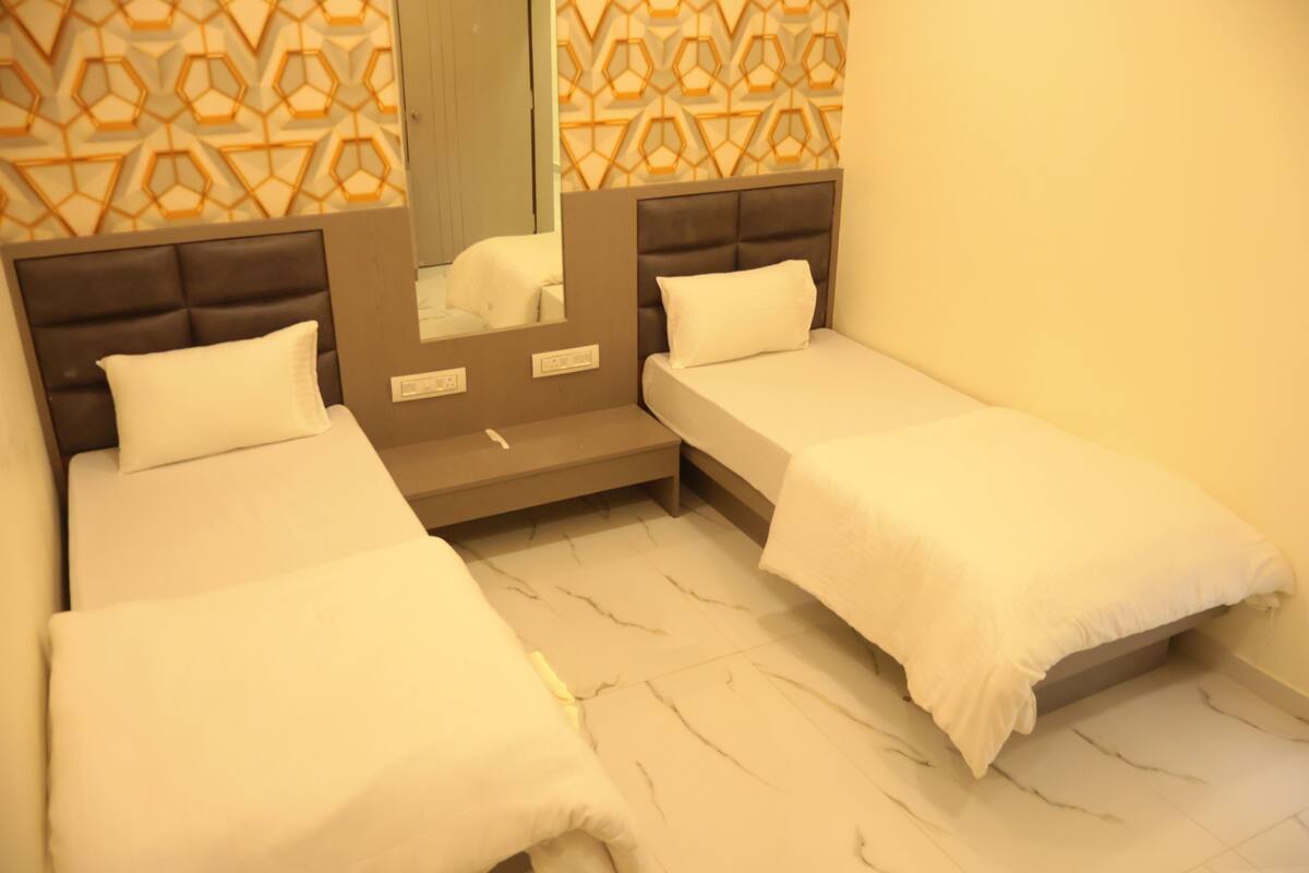A hotel room with two single beds, a mirror, and a patterned wall.