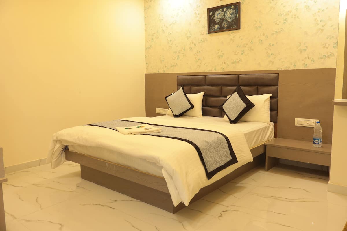 A hotel room with a large bed, a nightstand, and a wall-mounted outlet.