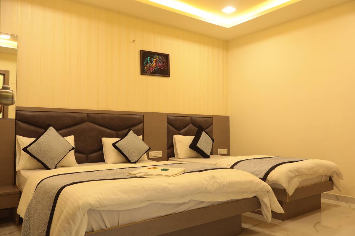 A hotel room with two beds, a headboard with a tufted design, and a small painting on the wall.