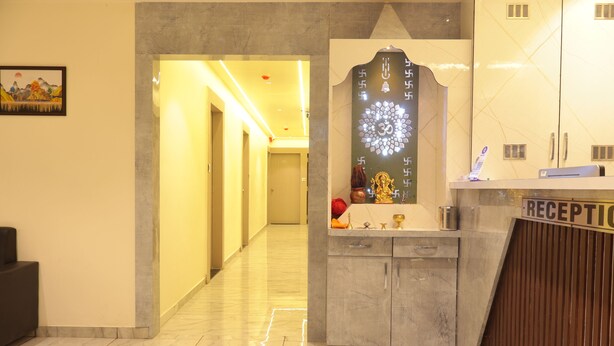 A reception area with a marble floor, a reception desk, and a wall-mounted decorative piece. - Hotel NS Residency (Ahmedabad)