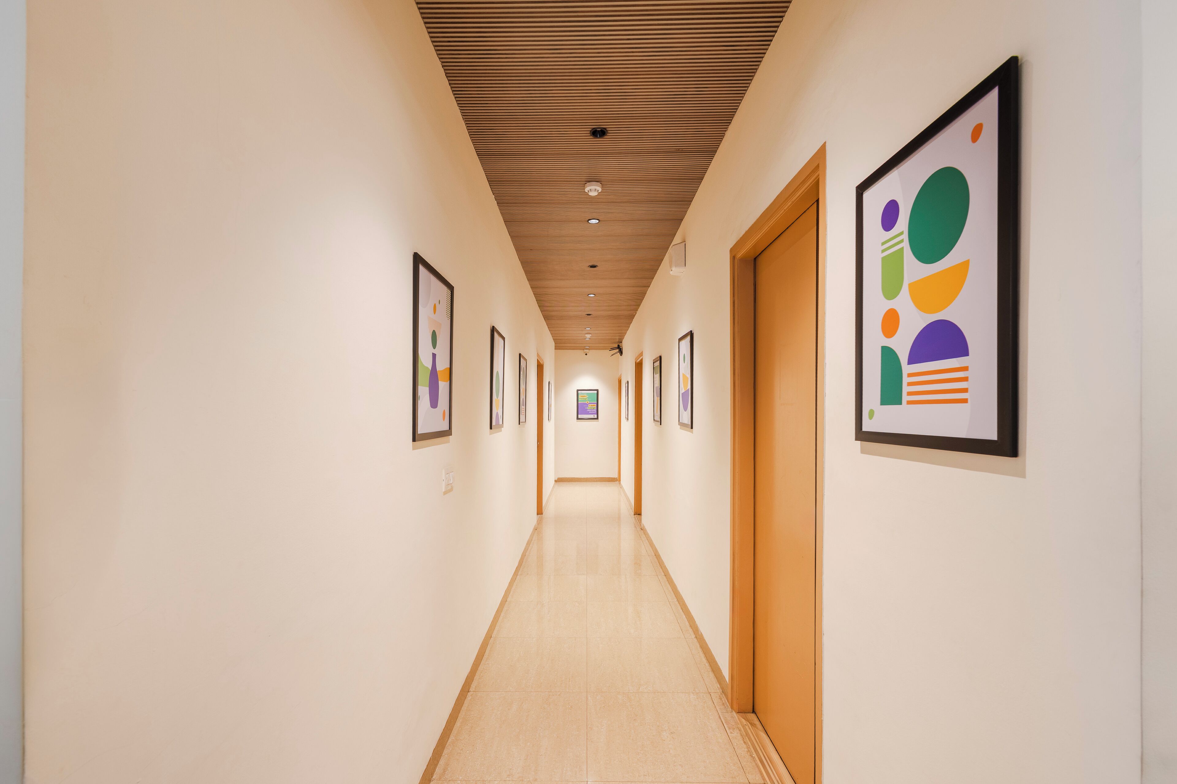 A long, narrow hallway with wooden ceiling panels and framed artwork on the walls.