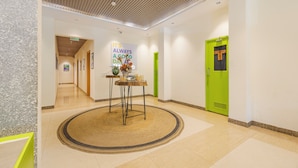 A hotel lobby with a wooden ceiling, a green door labeled 'WATERROOM', and a table with a sign saying 'IT'S ALWAYS A GOOD DAY'. - Treebo Ace Luxe (New Delhi)