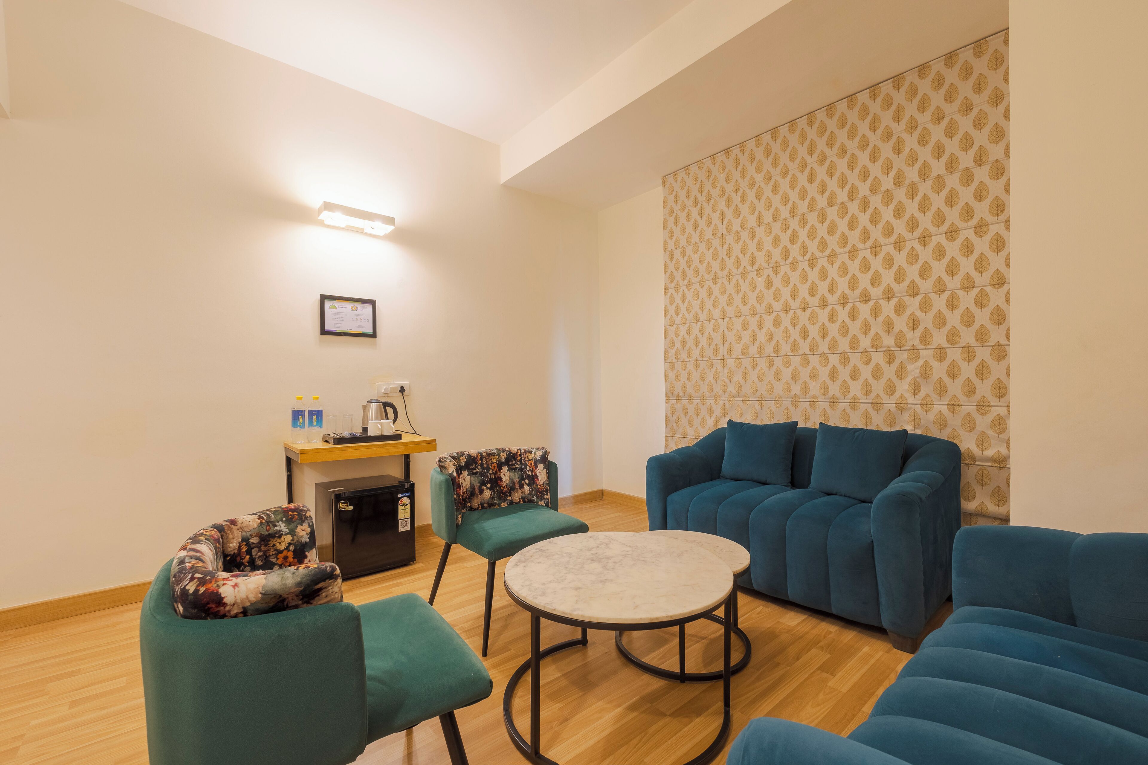 A modern living room with a sofa set, a round coffee table, and a small side table with a kettle and cups.