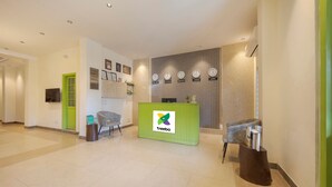 A reception area with a green desk, a chair, and a wall with clocks. - Treebo Ace Luxe (New Delhi)