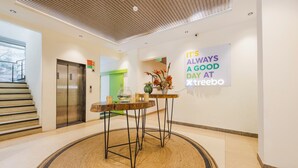A modern lobby with a wooden ceiling, a staircase, an elevator, and a sign that reads "It's always a good day at Treebo." - Treebo Ace Luxe (New Delhi)