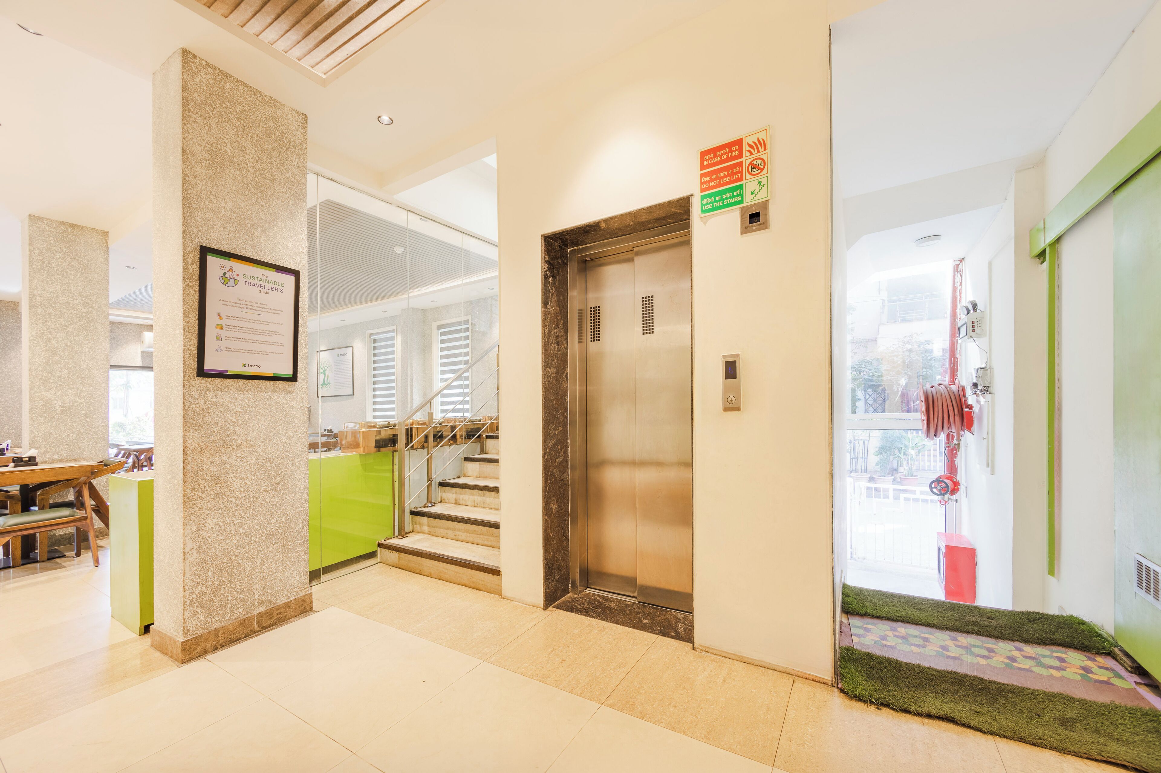 A hotel lobby with a reception desk, a staircase, and an elevator.