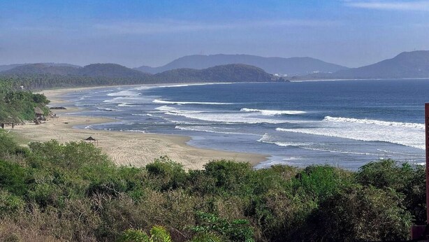 A coastal landscape with a beach, ocean waves, and distant hills. - Luxury Eco in Troncones Casa Mia (Troncones)