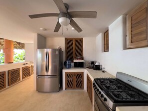A modern kitchen with a stainless steel refrigerator, a gas stove, and a ceiling fan.