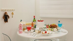 A table with various food items and drinks, including a cake, fruits, and a bottle of wine.