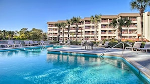 En swimmingpool med liggestole og en hotelbygning i baggrunden.