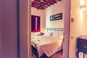 A bedroom with a bed, a nightstand, a lamp, and a painting on the wall. - Casa Mortella C: A graceful two-story apartment that is part of an ancient manor house, with Free WI-FI. (Monsano)
