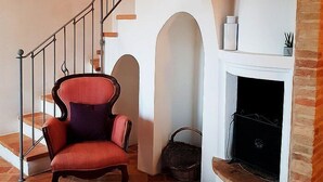 Una escalera con barandilla metálica, un sillón rojo y una chimenea con repisa blanca.