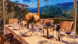 Un montaje para comer al aire libre con una mesa dispuesta para seis personas, rodeada de sillas, y un paisaje montañoso de fondo.