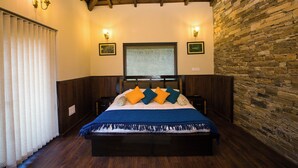 Ein Schlafzimmer mit Holzboden, Steinwand und einem Bett mit blauer und weißer Bettdecke.