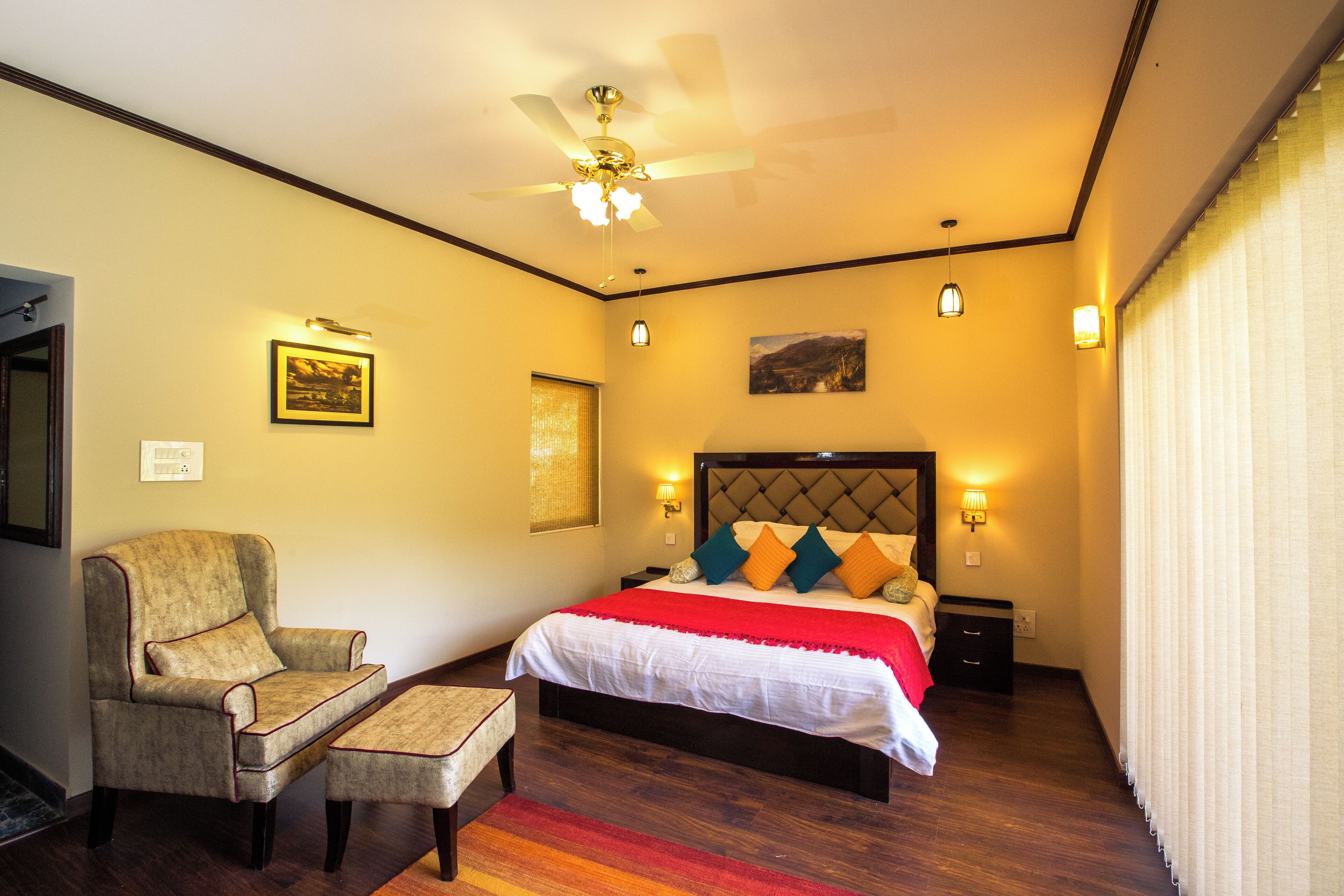 Une chambre d’hôtel avec un lit, une chaise, une table de chevet et un ventilateur de plafond.