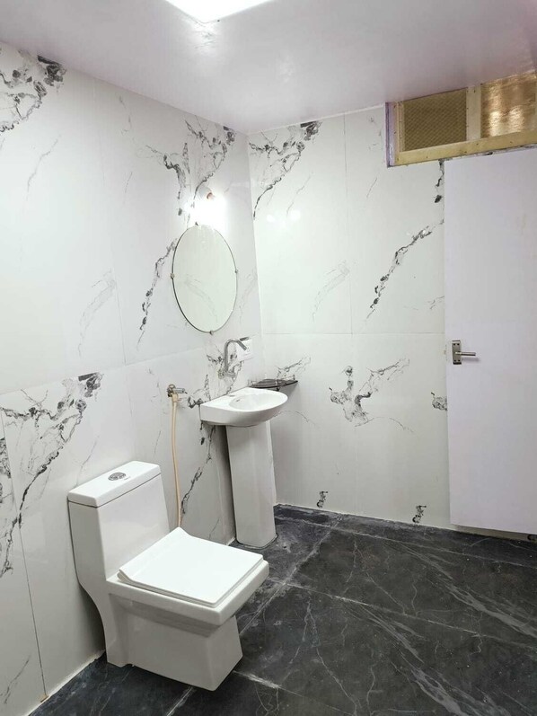 A bathroom with a toilet, sink, and mirror.