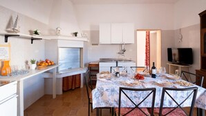 A compact kitchen with white cabinets, a dining table set with plates and glasses, and a TV in the corner.
